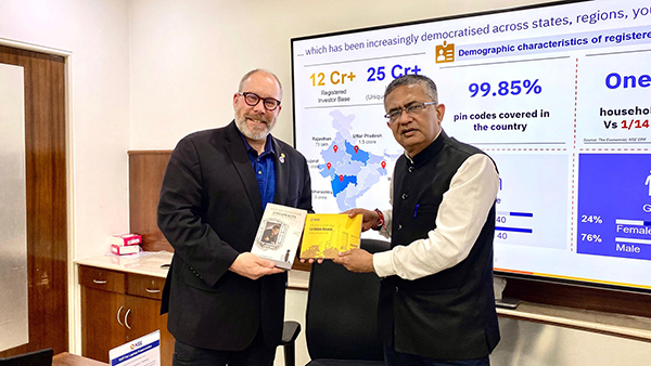 Dr. Scott Spangler exchanging books and educational materials with Shri Ashishkumar Chauhan at the National Stock Exchange of India.